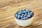 Freshly picked blueberries in white bowl. Juicy and fresh blueberries on rustic table. Bilberry on wooden Background. Blueberry an