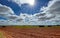 Freshly plowed fields of cereal crops on a spring day with clouds in the sky and the sun filtering through the clouds