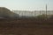 Freshly plowed spring field in cloudy weather and a power line crossing it