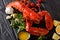 Freshly prepared lobster closeup with lemon, garlic, fresh tomatoes and herbs on a table. horizontal