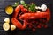 Freshly prepared lobster closeup with lemon, garlic, fresh tomatoes and herbs on a table. Horizontal top view