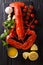 Freshly prepared lobster closeup with lemon, garlic, fresh tomatoes and herbs on a table. Vertical top view