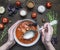 Freshly prepared tomato soup with basil, garlic and onion, thyme and seasonings, in a white plate, girl scooped up a spoon, on