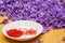 Freshly rolled strand saffron on white plate and background of purple saffron rose