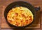 Freshly scrambled eggs in rustic pan on the cooking table