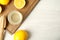 Freshly squeezed juice, lemons and reamer on white wooden table, flat lay. Space for text