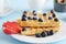 Freshly sung homemade Viennese or Belgian waffles with fresh strawberries and blueberries on a blue table. In the background is a