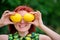 Freshness, healthy lifestyle and vitamins concept: smiling woman with red hair hiding her eyes behind two bright yellow lemons