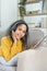 frican American sitting on a sofa using tablet and wearing headphones to relax