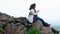 Frican American woman is sitting on a mountain edge enjoying the inspiring view