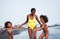 Frican sister twins running on the beach with smiling mother - Black family people having fun on summertime - Vacation, travel and