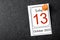 The Friday the 13th calendar with wooden push pin on black background