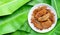 Fried bananas with sesame seeds on white ceramic round plate on banana leaves background.