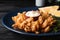 Fried blooming onion with dipping sauce served on dark wooden table, closeup