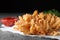 Fried blooming onion with dipping sauce served on grey table, closeup