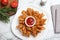 Fried blooming onion with dipping sauce served on white marble table, flat lay
