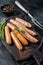 Fried Bratwurst or Hot Dogs sausages on a wooden board. Black background. Top View