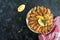 Fried capelin, sprats. Small fried fish on a plate on a black background. Top view