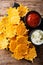 Fried cheddar cheese chips with herbs served with sauces close-up. Vertical top view