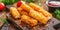 Fried cheese sticks with seasoning on dark wooden board