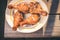 Fried chicken legs in a plate on a wooden table/Fried chicken legs in a plate on a wooden table. Top view. Sanny day