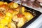 Fried chicken with potatoes on a baking sheet. A fork stuck in a fried piece of chicken