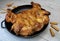 Fried chicken. On the table in a cast-iron pan, with a crisp, Golden crust. Bread sticks with sesame seeds. Wooden background
