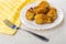 Fried chicken winglets in breading in plate, yellow napkin, fork