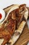 Fried chicken on a wooden board with sauce. Appetizing hearty food. Close-up. Vertical