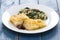 Fried codfish with bread and spinach on white plate