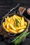 Fried Crinkle French fries potatoes in a pan. Black Wooden background. Top view