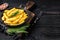 Fried Crinkle French fries potatoes in a pan. Black Wooden background. Top view. Copy space