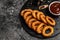 Fried crispy onion rings served on round black stone tray, american unhealthy calories meal. Delicious pub style, appetizer,