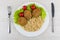 Fried cutlets, lettuce, tomatoes, brown rice in plate, knife, fork