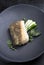 Fried Danish skrei cod fish filet with baby zucchini and lettuce on a modern design plate