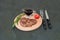 Fried, delicious veal, beef or pork steak, tomato, rosemary and soy sauce for meat on round wooden board, knife and fork