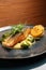 Fried dorado fish and mashed potato on a black plate