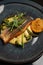 Fried dorado fish and mashed potato on a black plate