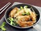 fried dumplings and sunflower seedling in teflon frying pan on gray tablecloth and silver chopsticks on brown wooden table top