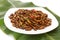 Fried edible insects on white plate and green leaf