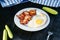 Fried egg with bacon, sliced cucumber, fork and towel