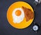 Fried egg and bread on the plate and alarm clock on the black ba