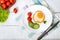 Fried egg in a circle of sweet pepper on a white plate with fresh vegetables