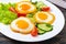 Fried egg in a circle of sweet pepper on a white plate with fresh vegetables on a wooden background.