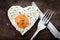 Fried egg with heart shape and cutlery on wooden background