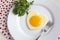 Fried egg in a heart shape with Rocket and fork in a white plate