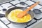 Fried egg-omelette from chicken eggs in a frying pan on the stove. The cooking process