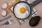 Fried egg on the pan, fork and knife, avocado, egg shells, dish towel.