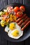 fried egg, sausages, pasta farfalle and tomato close-up. Vertical top view