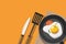 Fried egg and tomato in frying pan isolated on orange background.